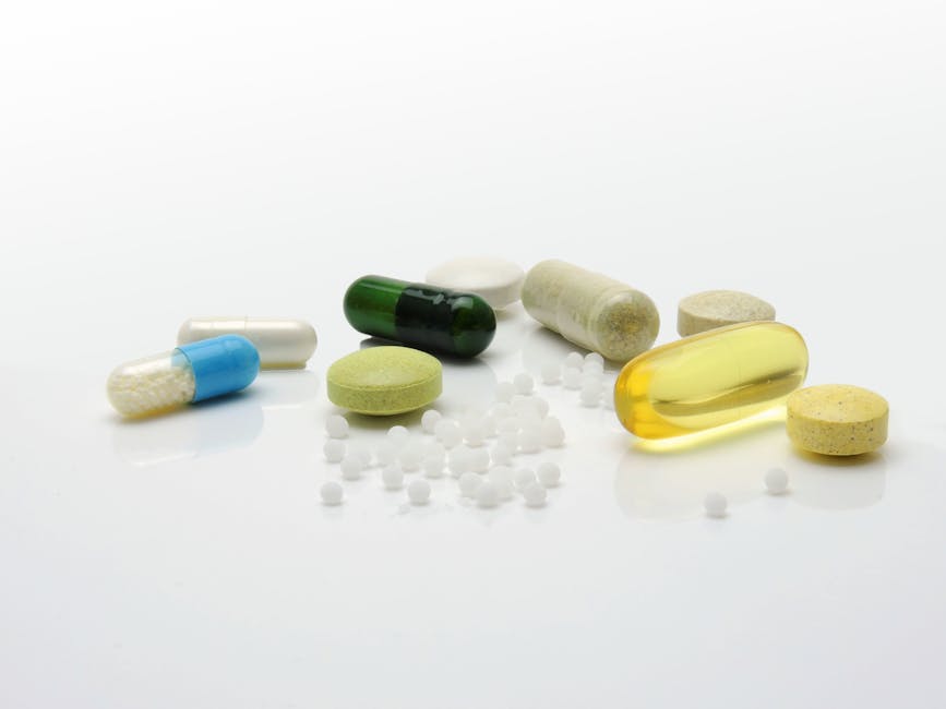 Close-up of various pills and capsules on a white surface, representing healthcare.