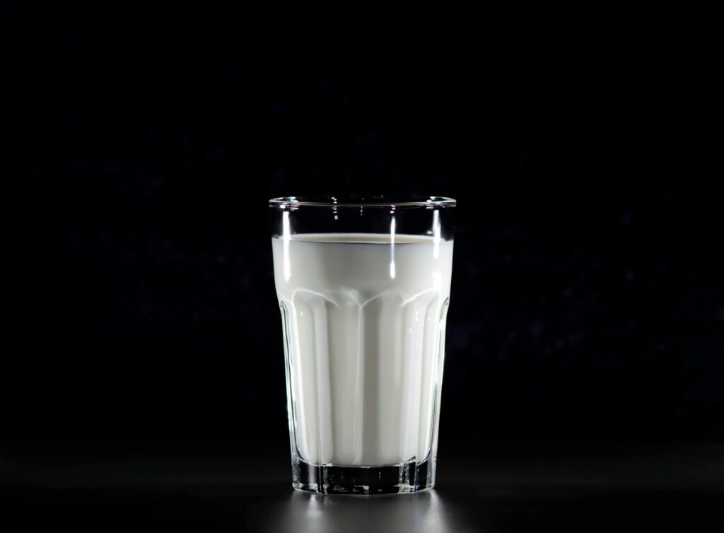 A glass of fresh milk against a black background, emphasizing simplicity and nutrition.