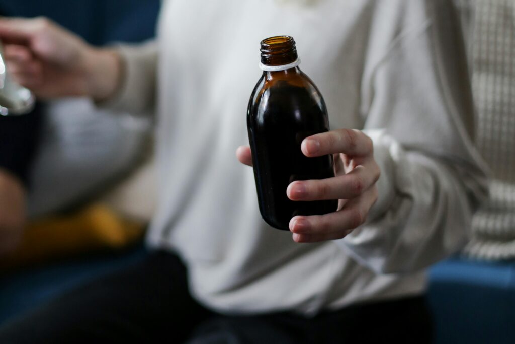 Close view of a person holding an amber medicine bottle, signifying health care and treatment.
