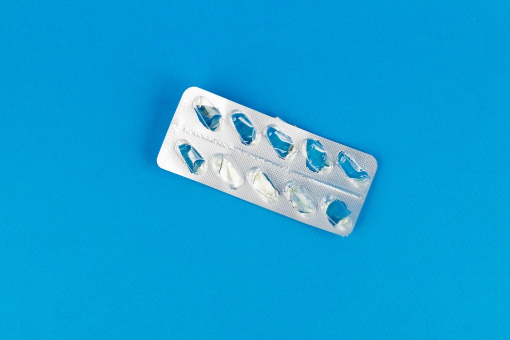 Top view of an empty blister pack on a bright blue background, highlighting medication and healthcare concept.