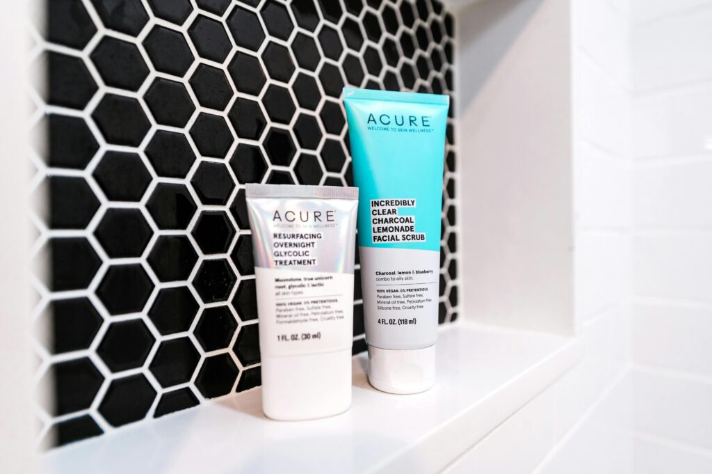 Close-up of Acure skincare products on a stylish black hexagonal tile background.