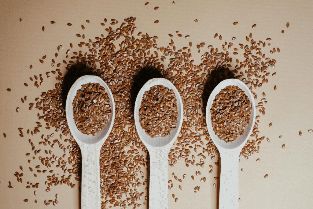 Flat lay of organic flaxseeds in wooden spoons showcasing natural nutrition and texture.