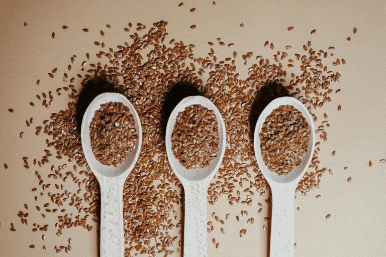 Flat lay of organic flaxseeds in wooden spoons showcasing natural nutrition and texture.